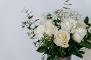 Bouquet of delicate white roses with fresh verdant leaves and stems on white background